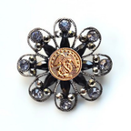 Decorative brooch with gold Marines inspired center and black and silver floral design on a white background