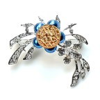 Decorative brooch with blue beads and gold center on a white background