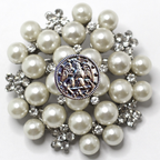 Brooch with pearls and a central emblem on a white background