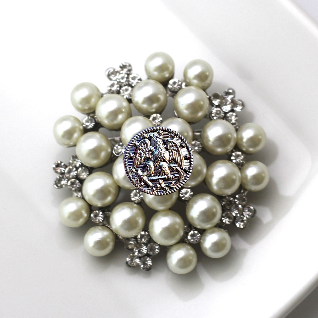 Pearl brooch with decorative center on a white background