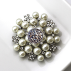 Pearl brooch with decorative center on a white background