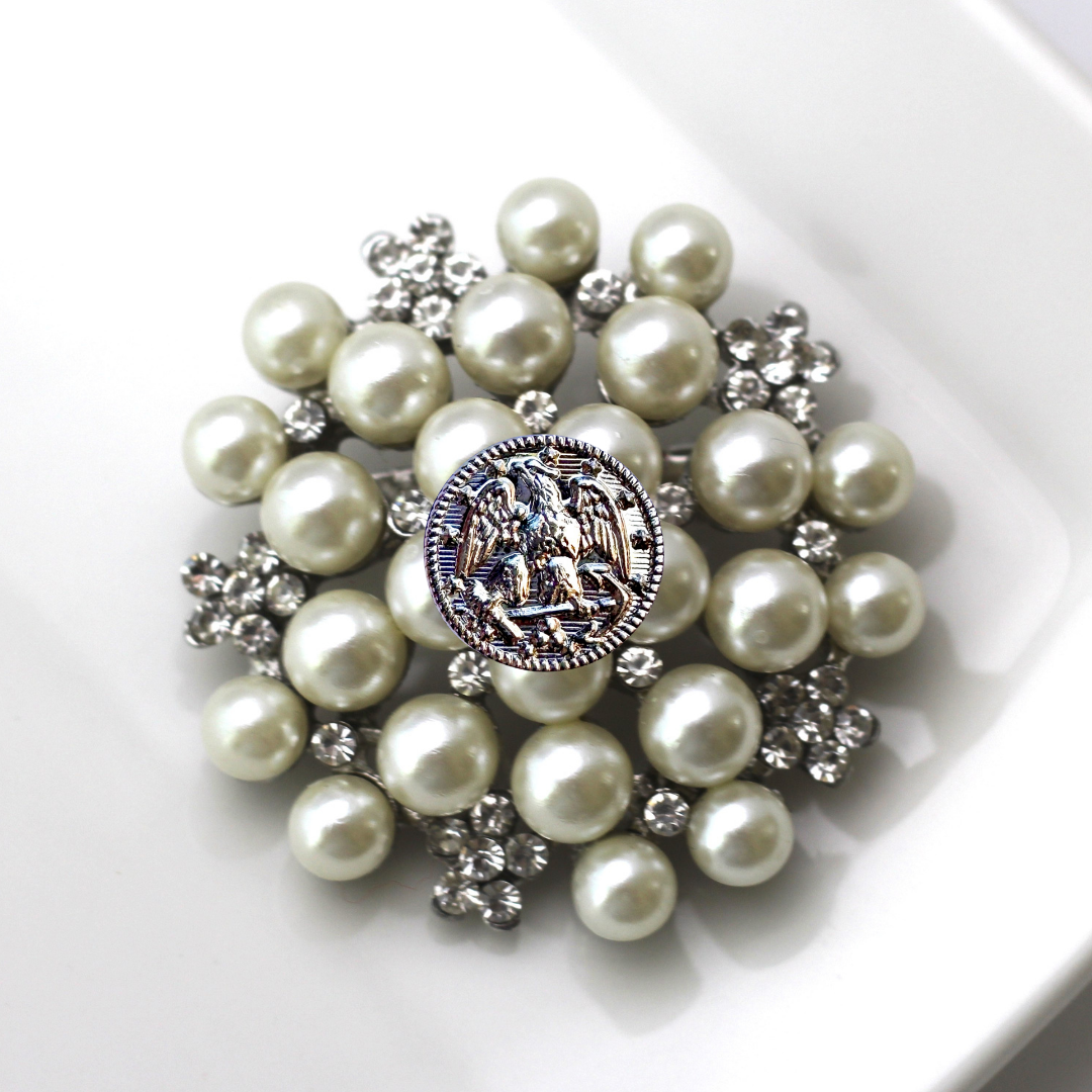Pearl brooch with decorative center on a white background