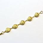 A gold-plated linked bracelet with metallic buttons attached to it, displayed against a white background.