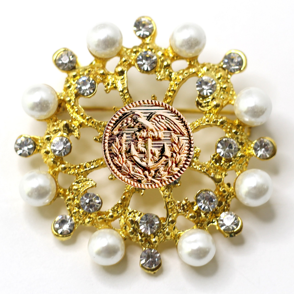 Decorative brooch with gold elements, pearls, and a Coast Guard emblem on a white background