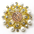 Decorative brooch with gold elements, pearls, and a Coast Guard emblem on a white background