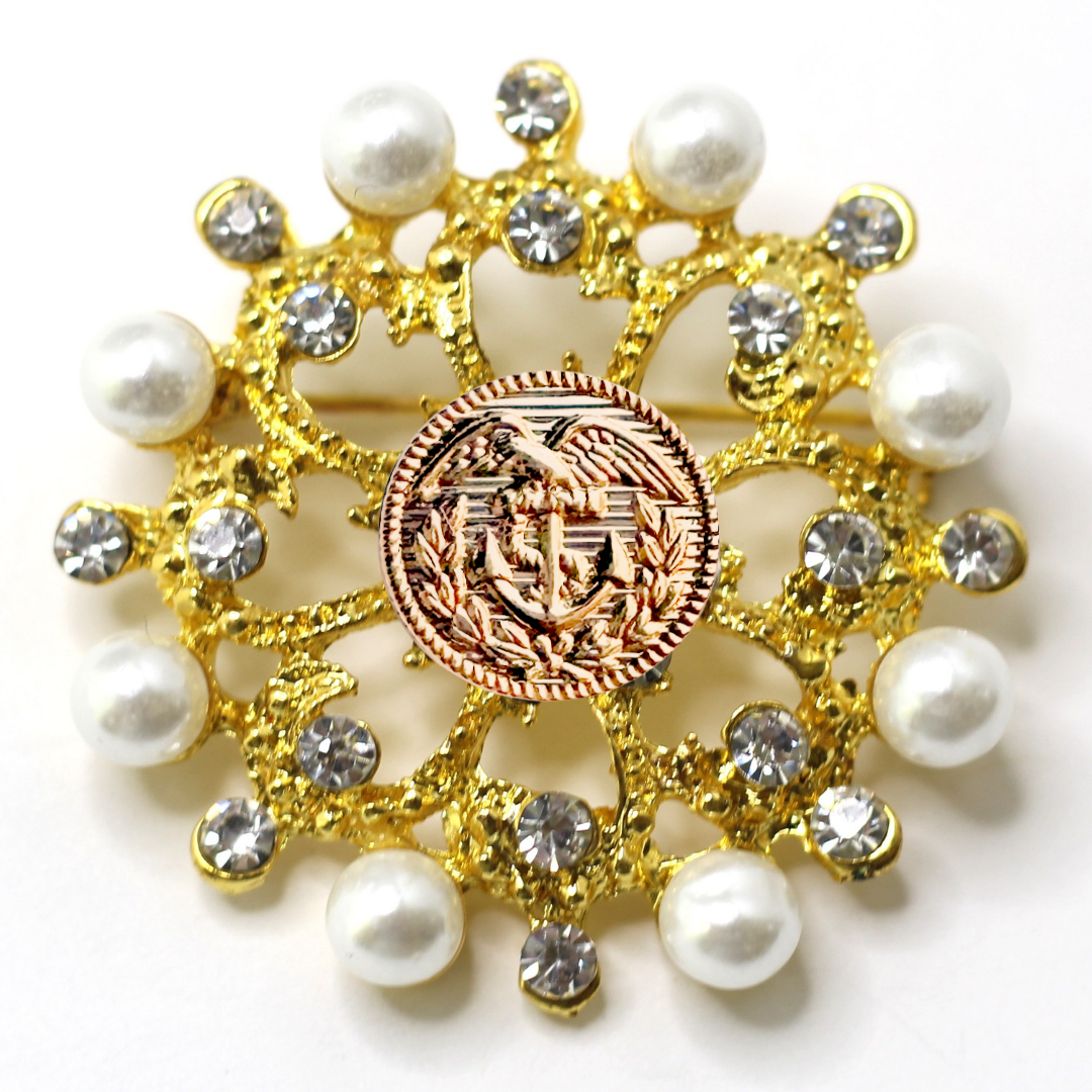 Decorative brooch with gold elements, pearls, and a Coast Guard emblem on a white background