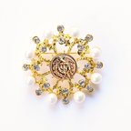 Decorative brooch with gold elements, pearls, and a Coast Guard emblem on a white background