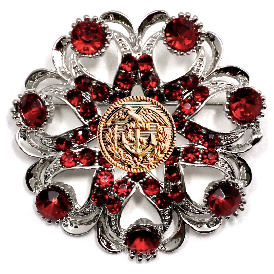Decorative brooch with red gemstones and a gold Coast Guard center on a white background