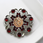Decorative brooch with red gemstones and a gold Coast Guard center on a white background