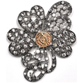 Decorative brooch with floral design and gold center on a white background