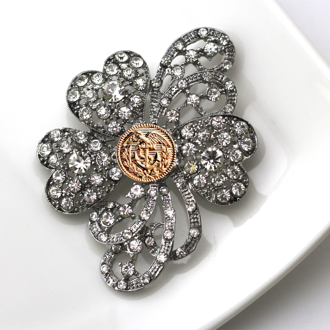 Decorative brooch with floral design and crystal-like embellishments on a white background