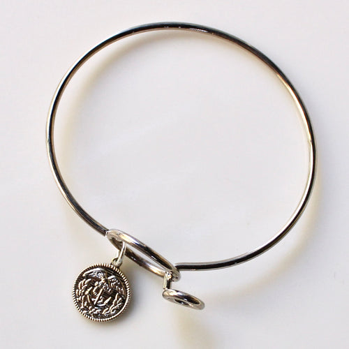 Silver bangle with a round charm on a white background