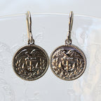 Pair of silver earrings with intricate designs on a white background