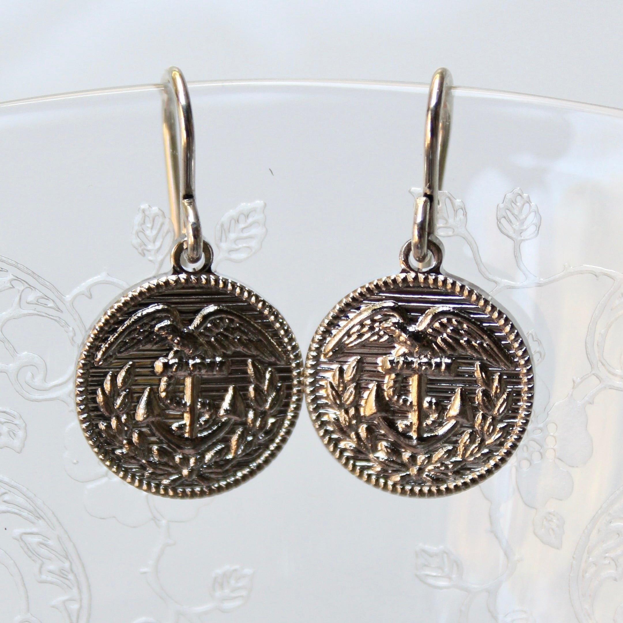 Pair of silver earrings with intricate designs on a white background