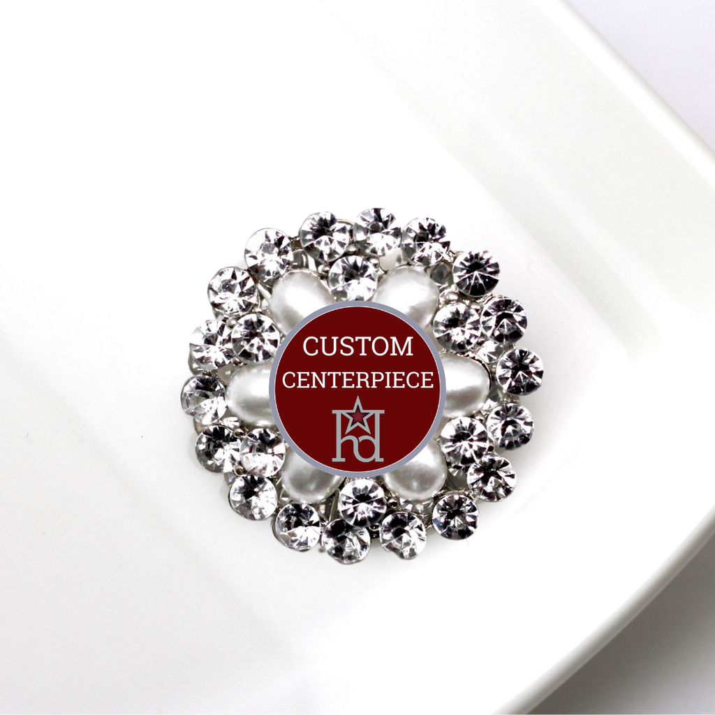 Decorative brooch with crystals and red center displaying 'Custom Centerpiece' text.