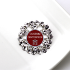 Decorative brooch with crystals and red center displaying 'Custom Centerpiece' text.