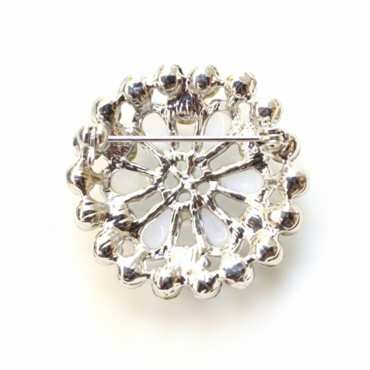 Silver brooch with clear gemstones on a white background