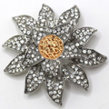 Decorative brooch with floral design and gold center on a white background