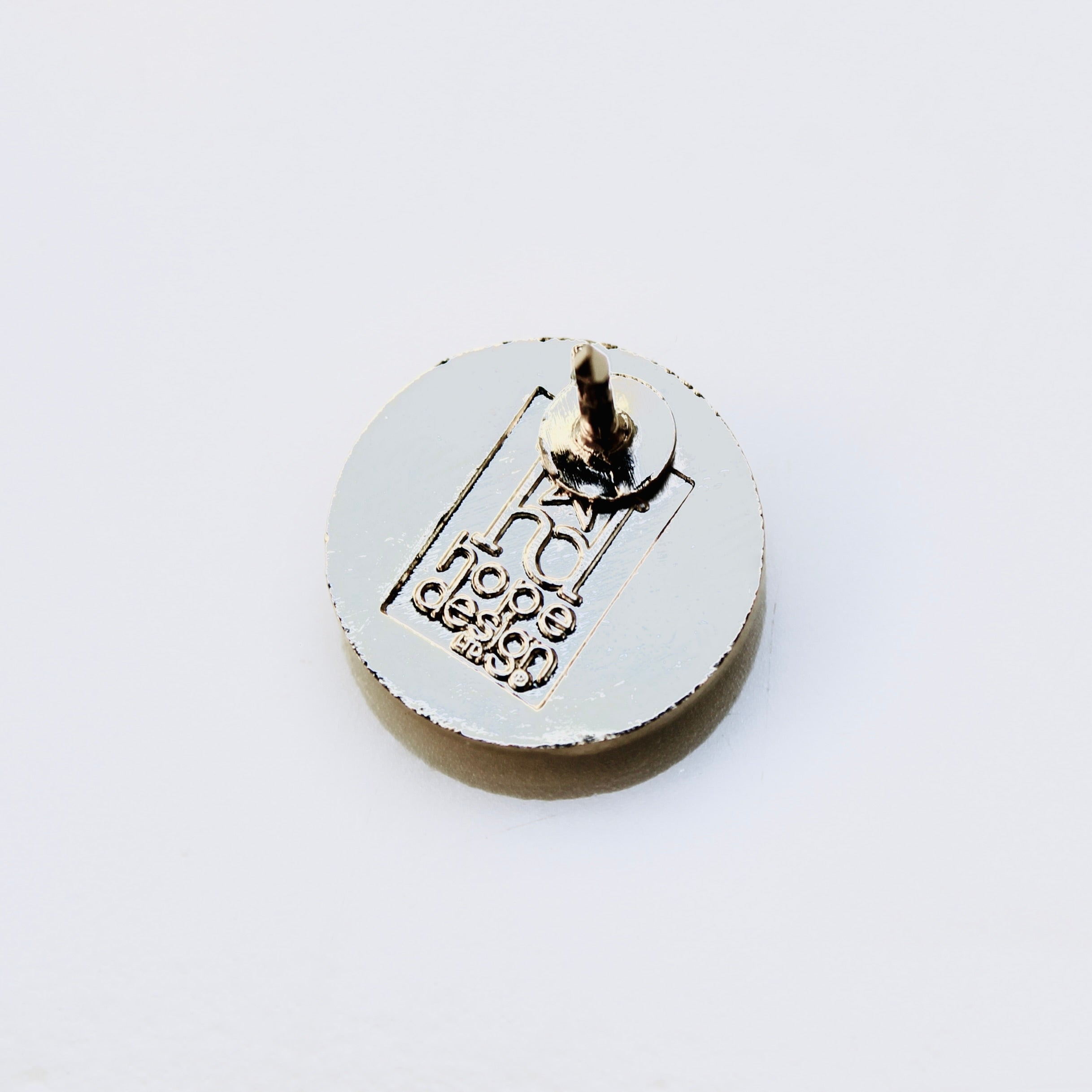 Round metal lapel pin back with branding on a white background