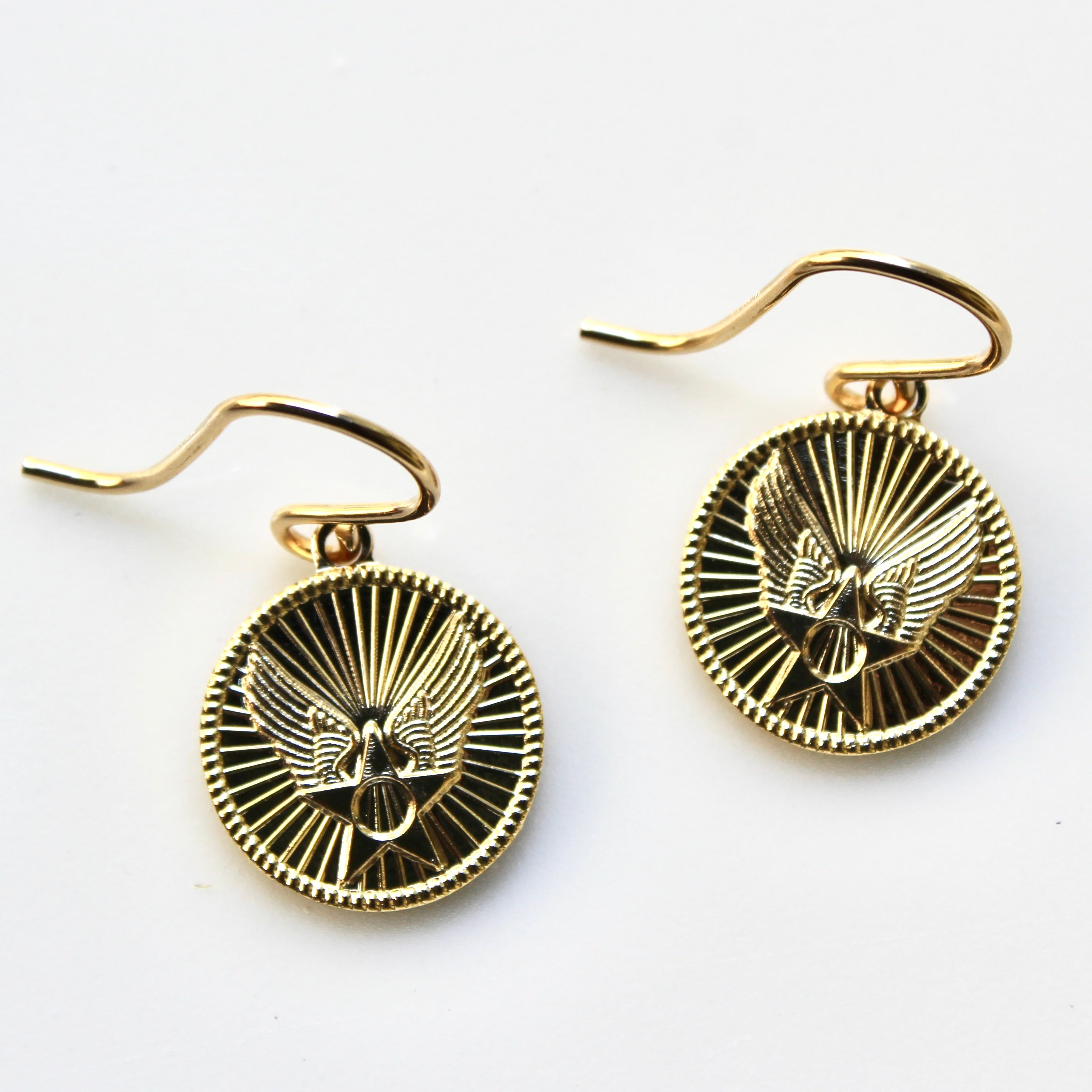 Gold earrings with an eagle design on a white background