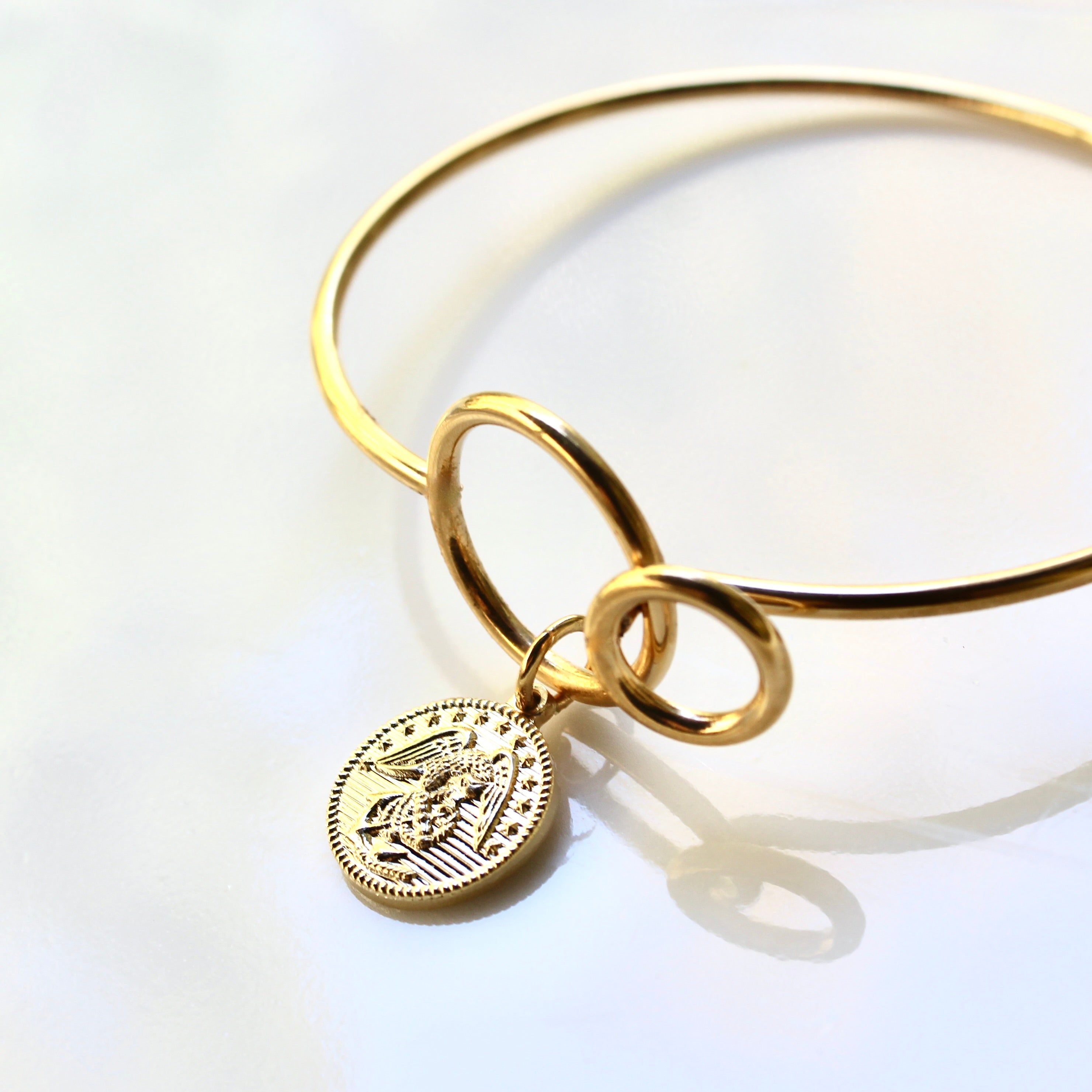 Gold bracelet with a round charm on a white background