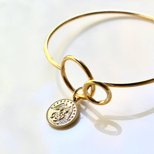 Gold bracelet with a round charm on a white background