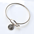 Silver bangle with a round charm on a white background