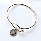 Silver bangle with a round charm on a white background