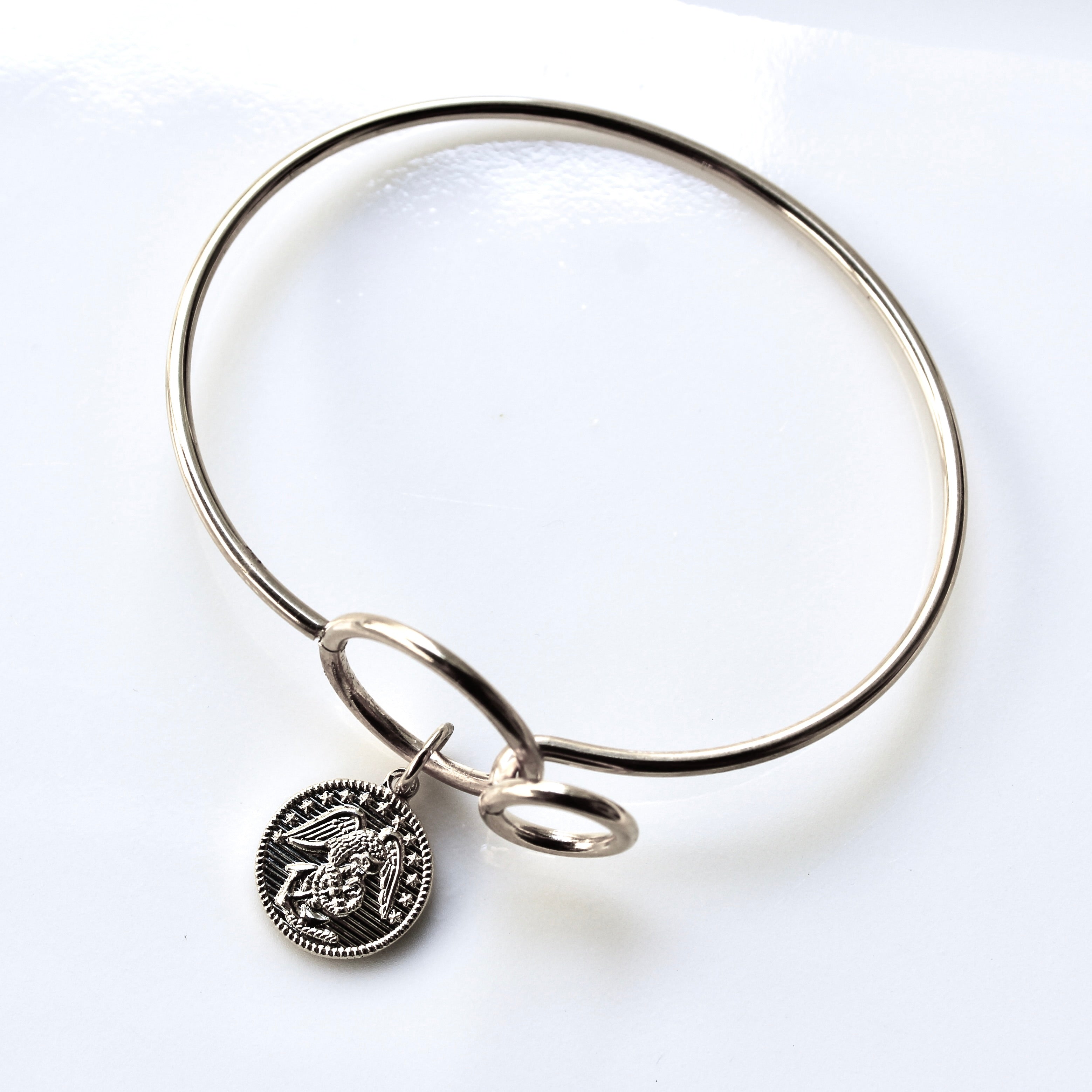 Silver bangle with a round charm on a white background