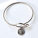 Silver bangle with a pendant on a white background