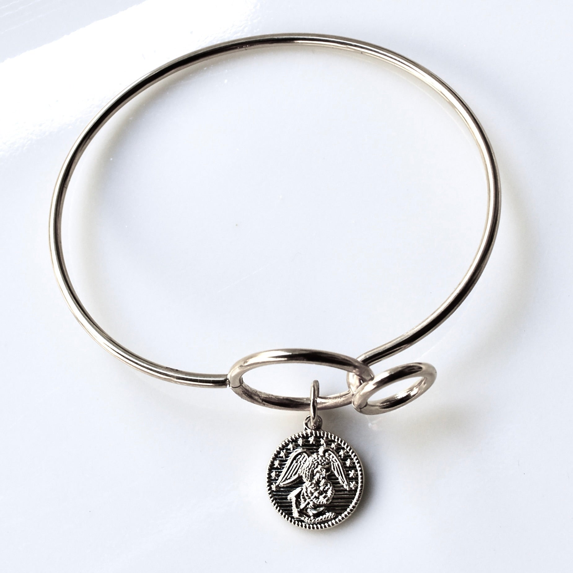 Silver bangle with a pendant on a white background
