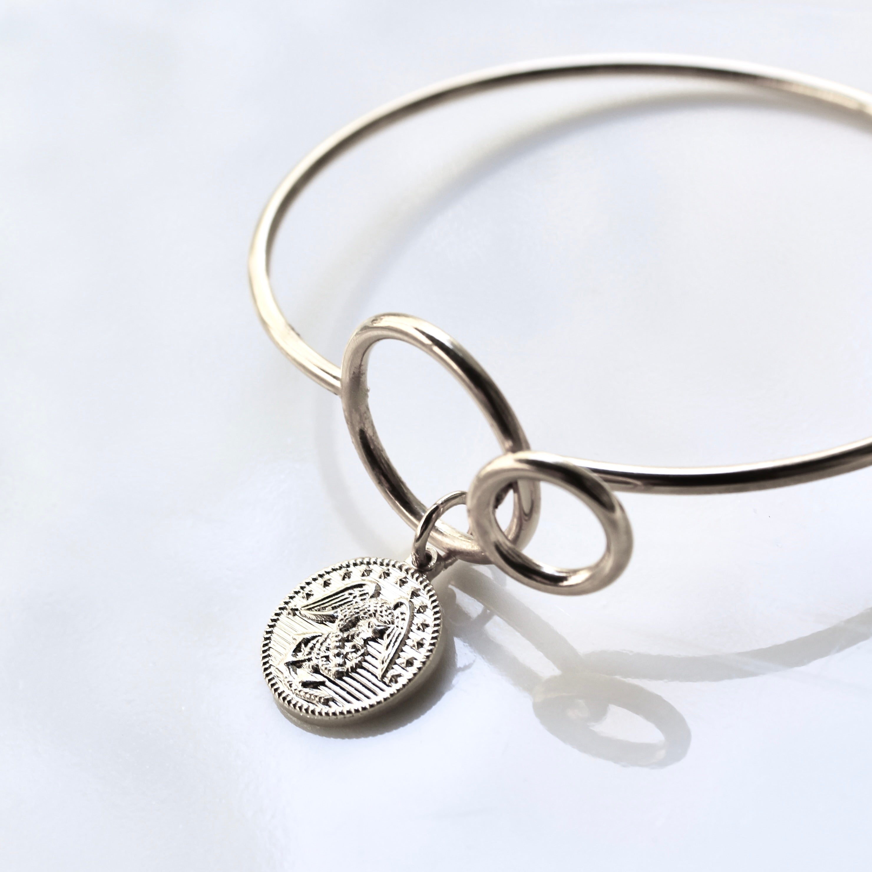 Silver bangle with a round charm on a white background