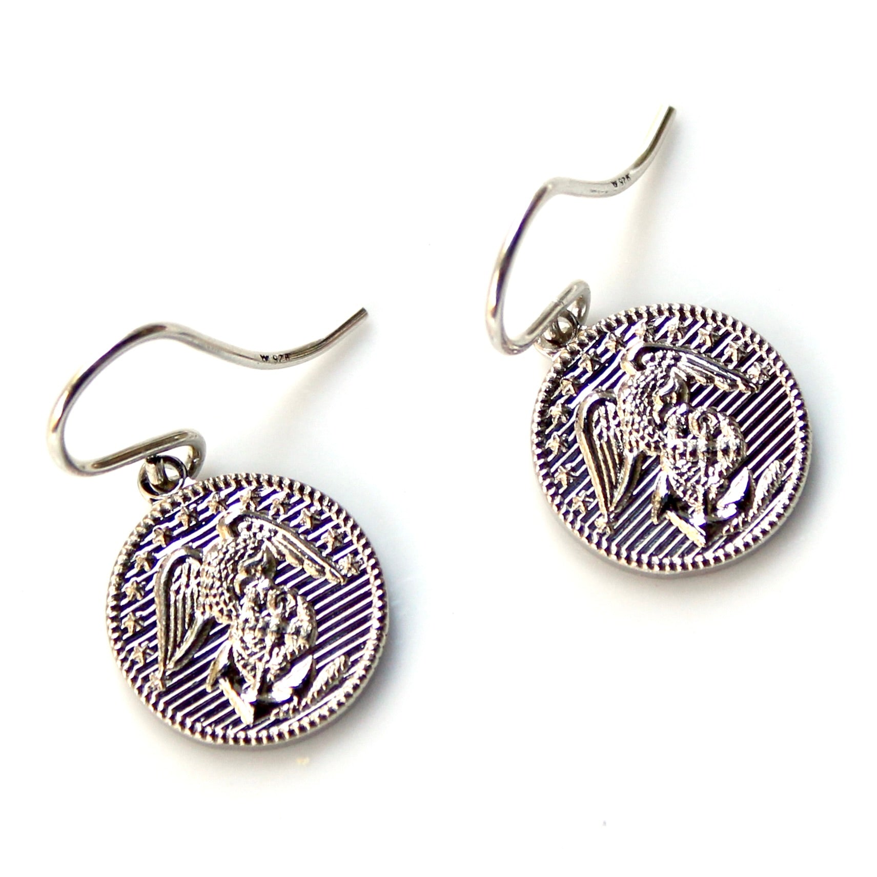 Pair of silver earrings with intricate designs on a white background
