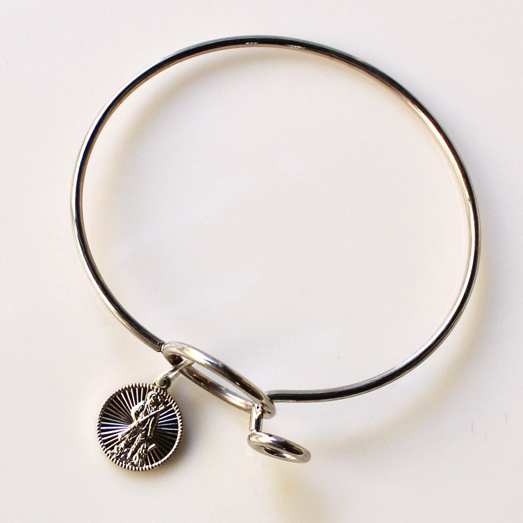 Silver bangle with a round charm on a light background
