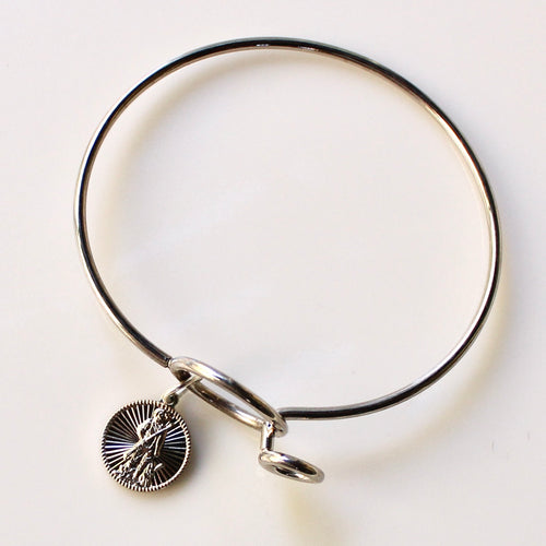 Silver bangle with a round charm on a light background