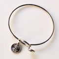 Silver bangle with a round charm on a light background