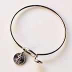 Silver bangle with a round charm on a light background