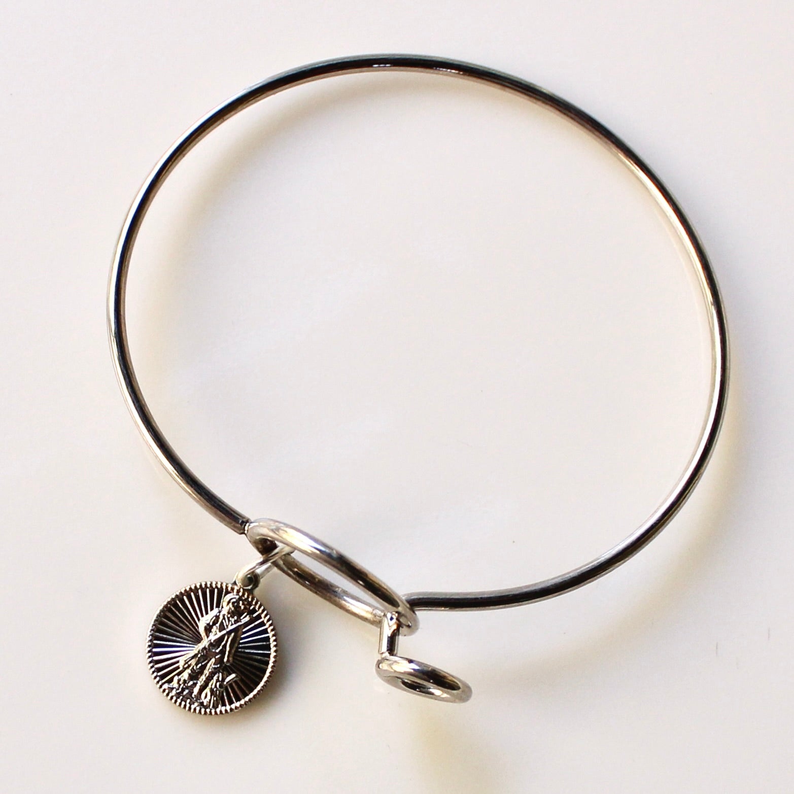 Silver bangle with a round charm on a light background