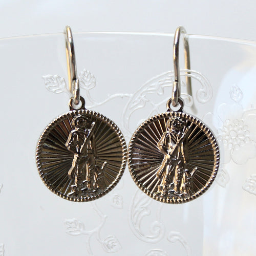 Pair of gold coin-shaped earrings on a decorative card