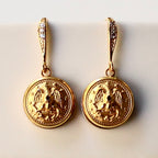 Gold earrings with intricate designs on a light background