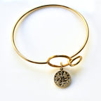Gold bangle with a pendant on a white background