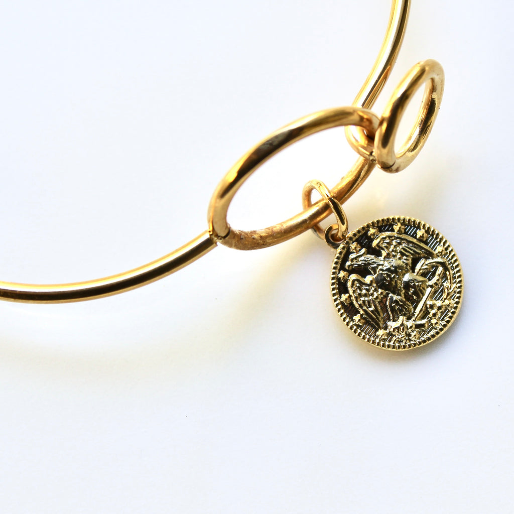Gold bracelet with a coin charm on a white background