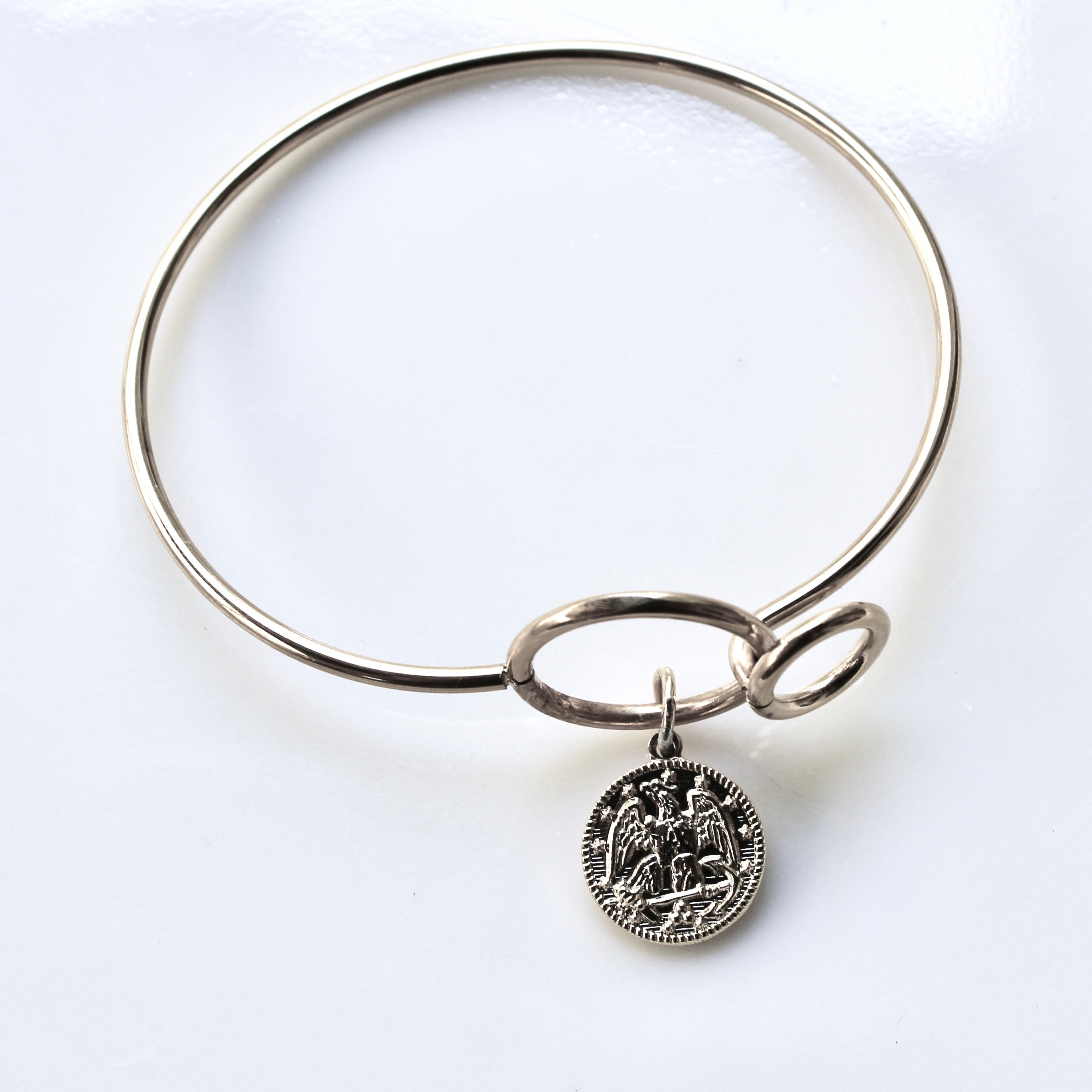 Silver bangle with a circular charm on a white background