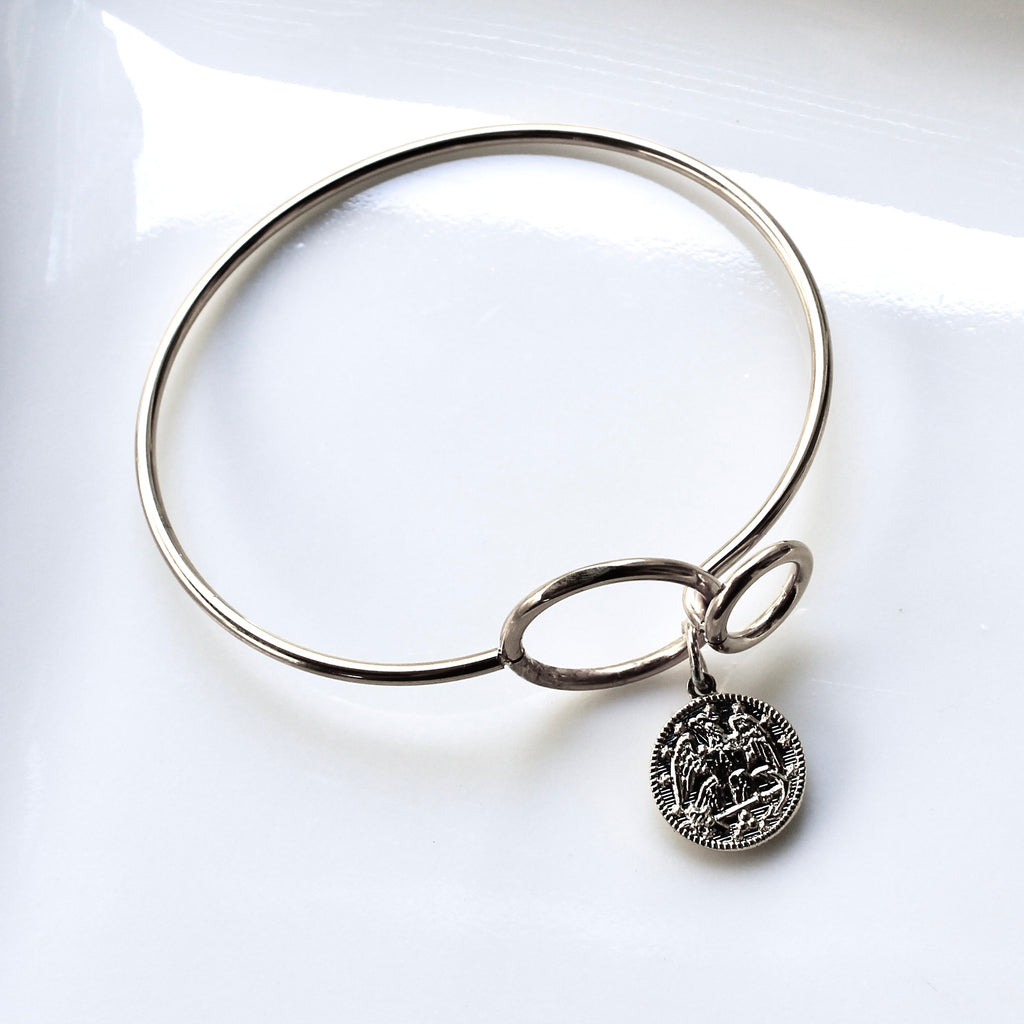 Silver bracelet with a circular charm on a white background