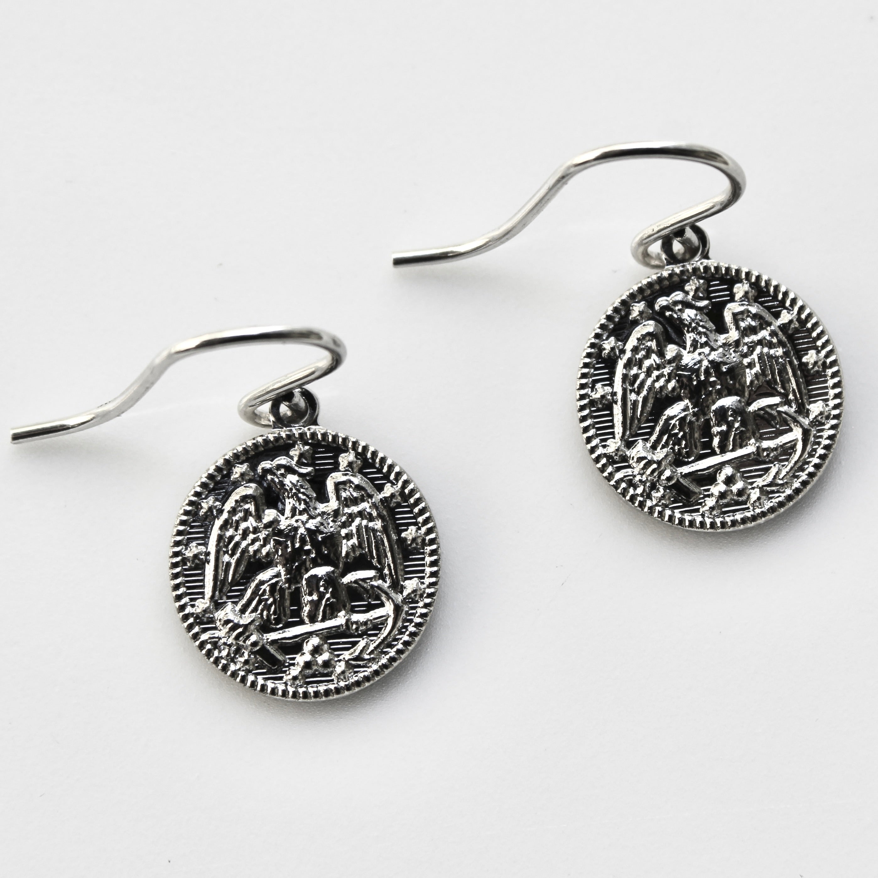 Pair of silver earrings with intricate designs on a white background