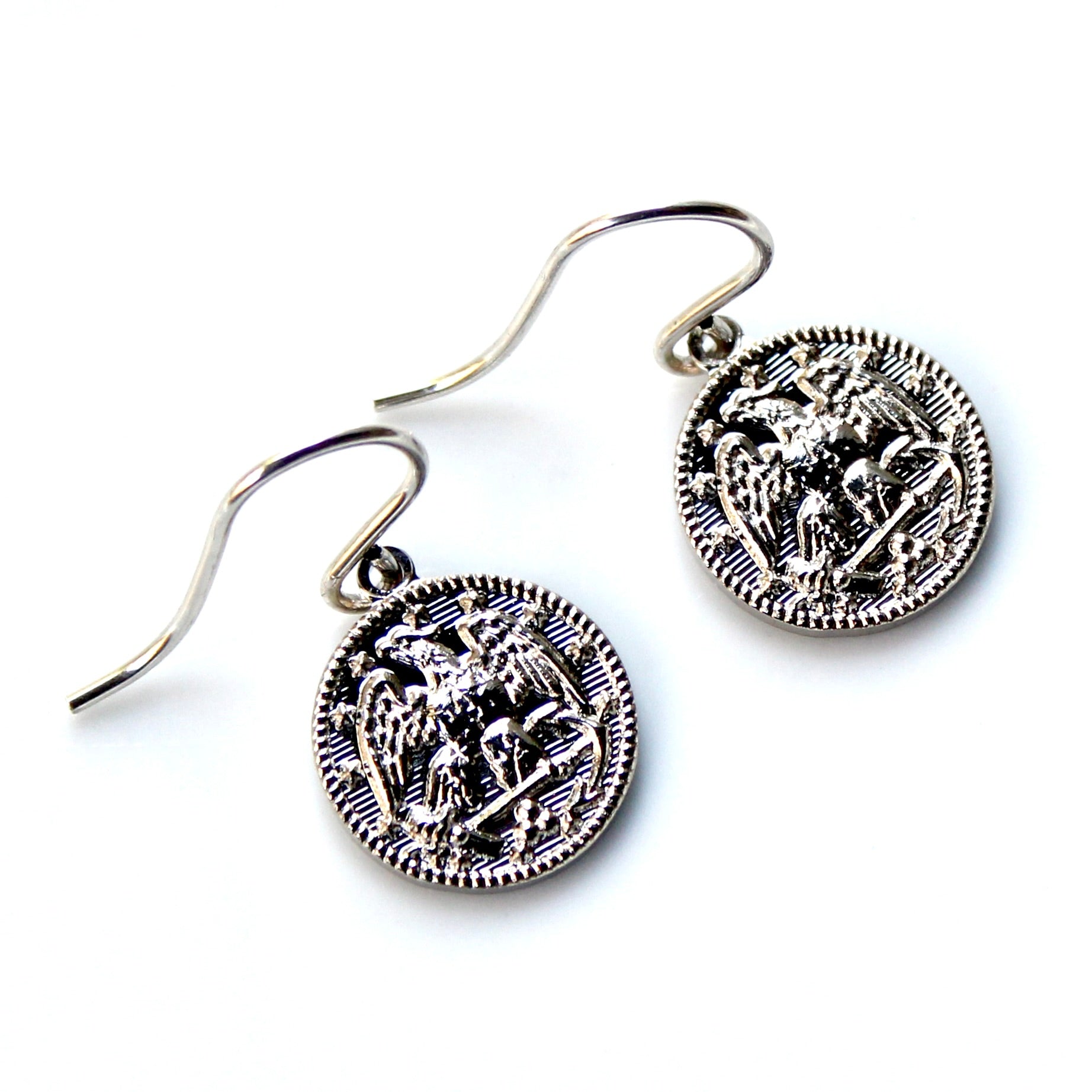 Silver earrings with intricate designs on a white background