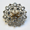 Decorative brooch with intricate design and gold accents on a white background