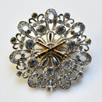 Decorative brooch with intricate design and gold accents on a white background