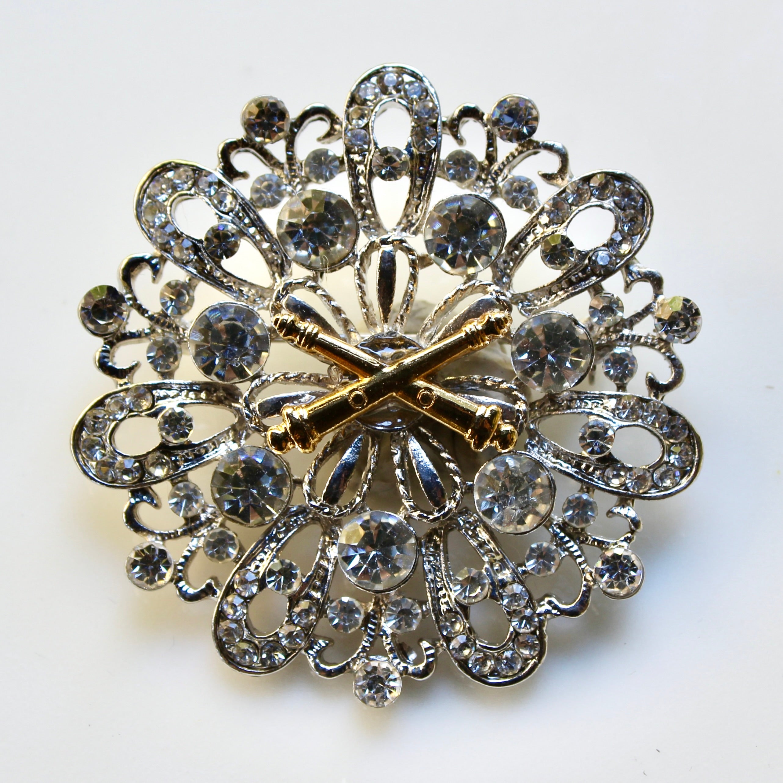 Decorative brooch with intricate design and gold accents on a white background