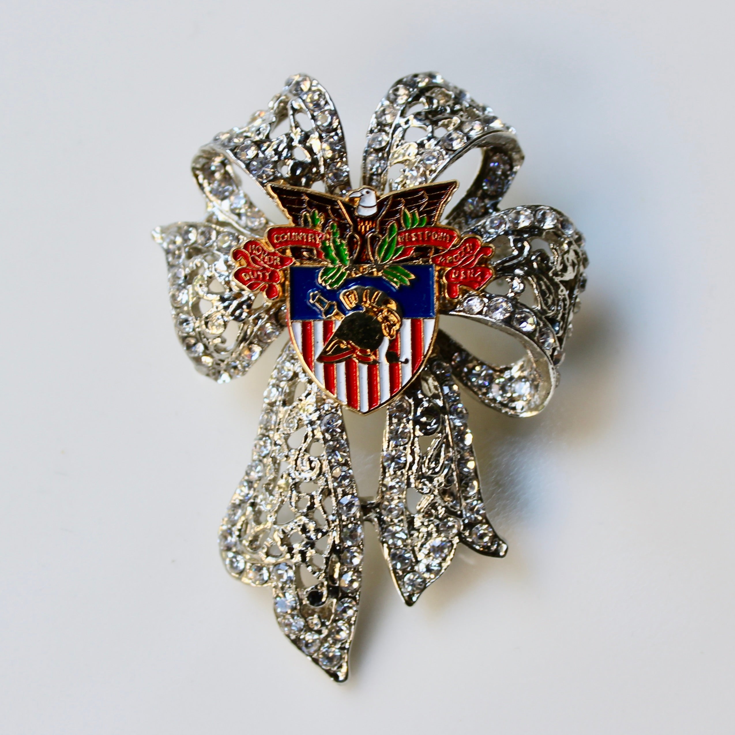 Decorative brooch with an eagle emblem and rhinestone accents on a light gray background